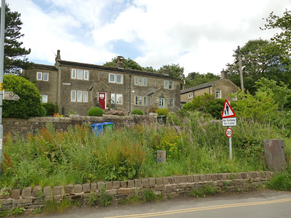 Old stone cottages above a bank of wildflowers on Bear Hill in Littleborough